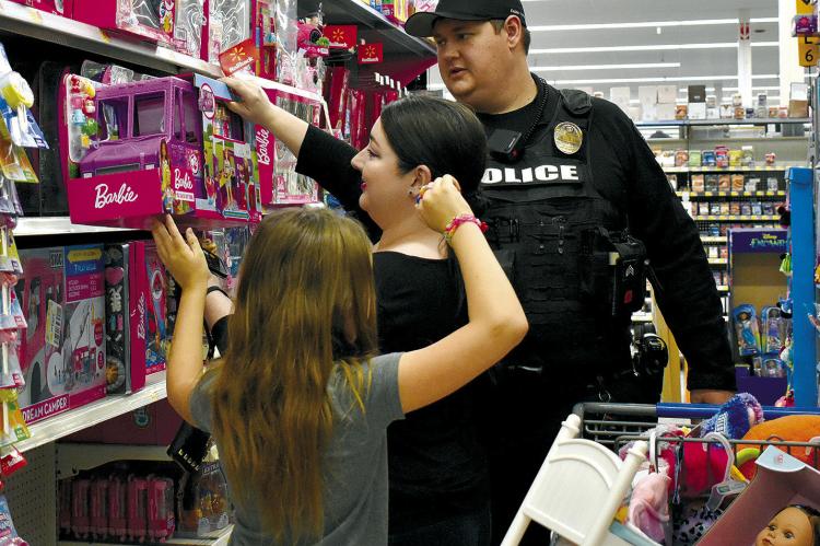 A NEW BARBIE TRUCK is coming home with Esmeralda Fox, left. Michela Fox and Sgt. Scott Sickles assist Fox with the selection during Shop with a Cop. TARA ALTIS | Staff
